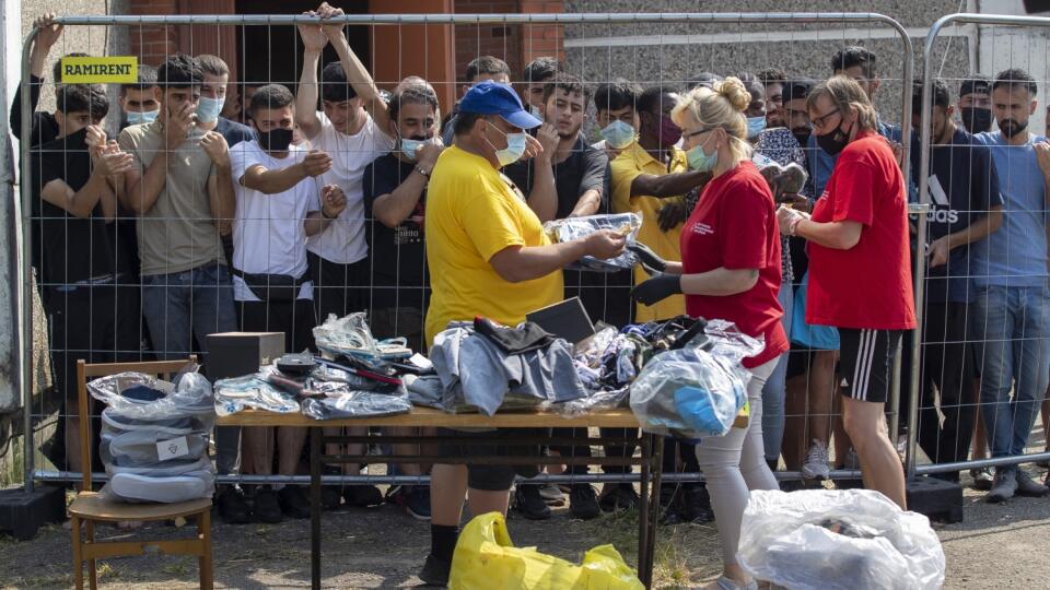KK34 Verebiejai - Litovčania rozdávajú veci migrantom, ktorí stoja za plotom v utečeneckom tábore v litovskej dedine Verebiejai 11. júla 2021. Litva v pondelok oznámila, že otvorí nový tábor pre nelegálnych migrantov prichádzajúcich zo susedného Bieloruska. Ako informovala agentúra Reuters, stalo sa tak v čase, keď Vilnius viní Minsk z úmyselného dovážania utečencov z iných krajín na hranice s Litvou. Tento rok prekročilo nelegálne litovské hranice z Bieloruska približne 1676 migrantov vrátane 1