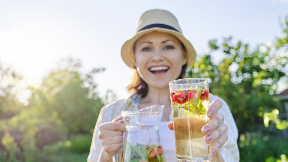 Spring summer refreshments, woman in nature holding jar of strawberry mint and lemon, cold refreshment drinks, healthy vitamin homemade drinks