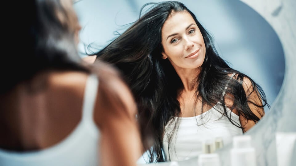 Beautiful,Early,Middle,Aged,Woman,Looks,Into,Bathroom,Mirror,Touches