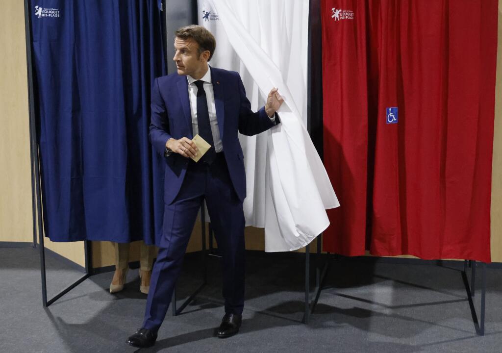 Francúzsky prezident Emmanuel Macron vychádza z priestoru na úpravu hlasovacích lístkov vo volebnej miestnosti počas hlasovania v prvom kole parlamentných volieb vo Francúzsku 12. júna 2022 vo francúzskom Le Touquet.