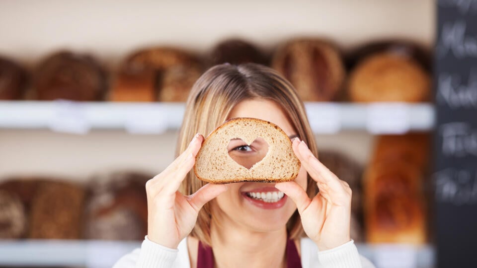 Smiling,Woman,Looking,Through,A,Bread,With,Heart,Hole