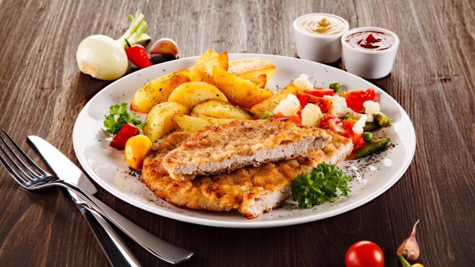 Fried pork chop, baked potatoes and vegetable salad