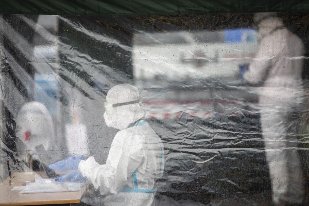 WA 38 Praha - Členovia volebnej komisie v špeciálnom ochrannom odeve čakajú na voličov, ktorí sú v karanténe na jednom zo stanovíšť počas parlamentných volieb v Českej republike v Prahe v stredu 6. októbra 2021. Voľby do Poslaneckej snemovne Parlamentu Českej republiky sa začali už v stredu. Ako prví môžu hlasovať ľudia, ktorí sa pre koronavírus nachádzajú v karanténe alebo izolácii. Tí môžu svoj hlas odovzdať priamo zo svojho auta na jednom z 82 stanovíšť. Oficálne sa volebné volebné miestnosti