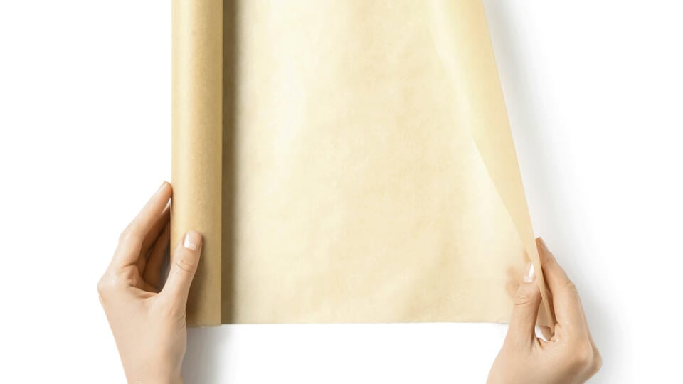Female hands with roll of baking paper on white background