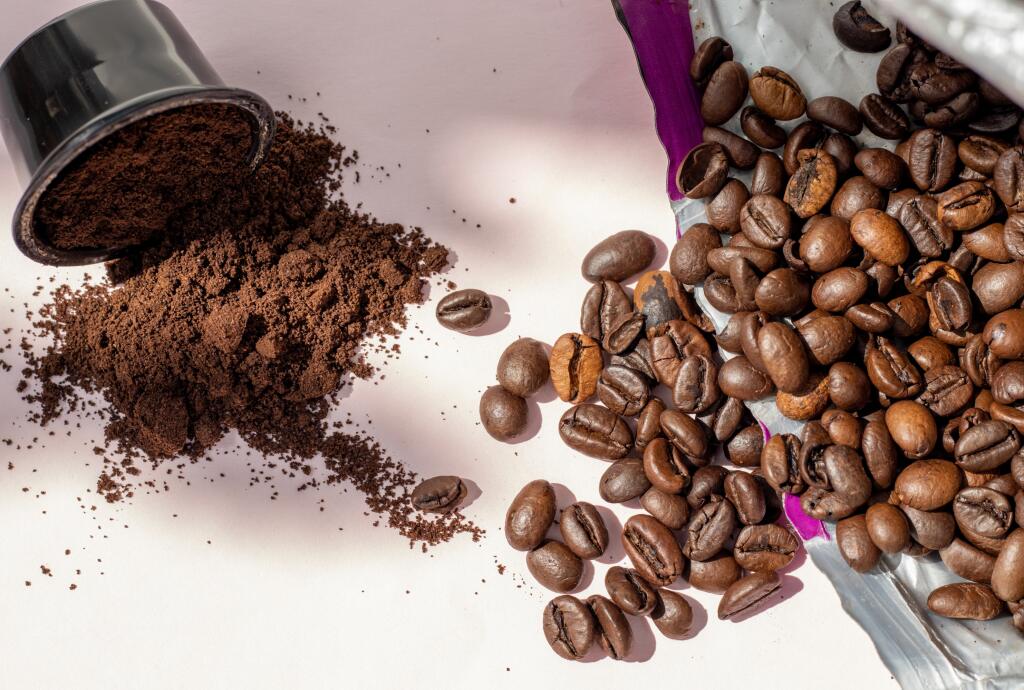 coffee beans vs coffee capsules concept.one coffee pod and beans from pack poured on table.sunny day,shadows.americano,espresso lovers,tasty drink,energy,caffeine.choosing the best option