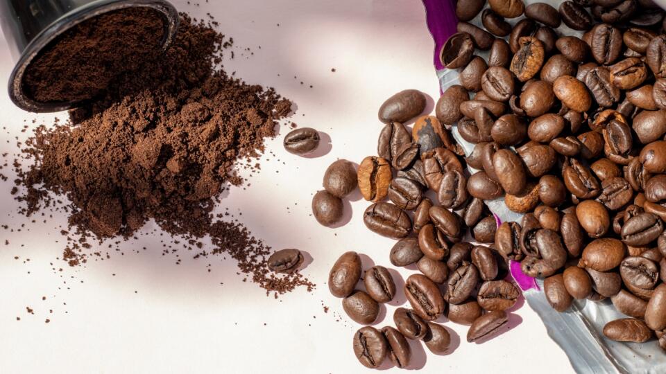 coffee beans vs coffee capsules concept.one coffee pod and beans from pack poured on table.sunny day,shadows.americano,espresso lovers,tasty drink,energy,caffeine.choosing the best option