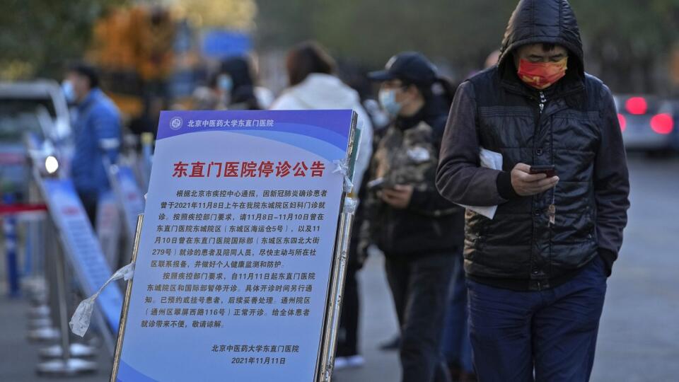 WA 39 Peking - Muž s ochranným rúškom proti šíreniu koronavírusu kráča okolo tabule, ktorá informuje o uzatvorení nemocnice z dôvodu návštevy pacienta pozitívneho na ochorenie COVID-19 v Pekingu v pondelok 15. novembra 2021. Čína zápasí s najväčším šírením koronavírusového variantu delta. Ukazujú to čísla oznámené v pondelok. Ľudia cestujúci z mesta Ta-lien, kde prípady tejto nákazy pribúdajú rýchlejšie než inde v krajine, musia v okolitých oblastiach dodržiavať prísnu karanténu. K 14. novembru