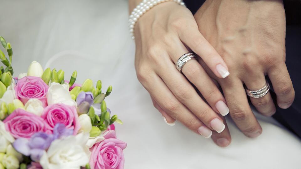 Hands of the groom and the bride with wedding bouquet