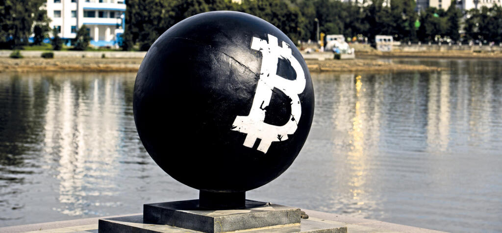 Bitcoin cryptocurrency symbol on a stone sphere monument painted black by unidentified persons in Oktyabrskaya Square