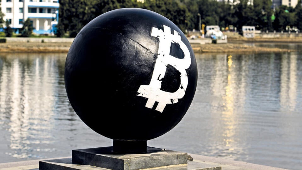 Bitcoin cryptocurrency symbol on a stone sphere monument painted black by unidentified persons in Oktyabrskaya Square
