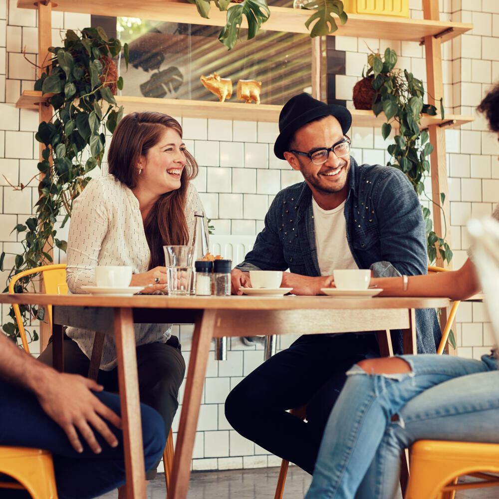 Young people having a great time in cafe. Friends smiling and sitting in a coffee shop, drinking coffee and enjoying together.