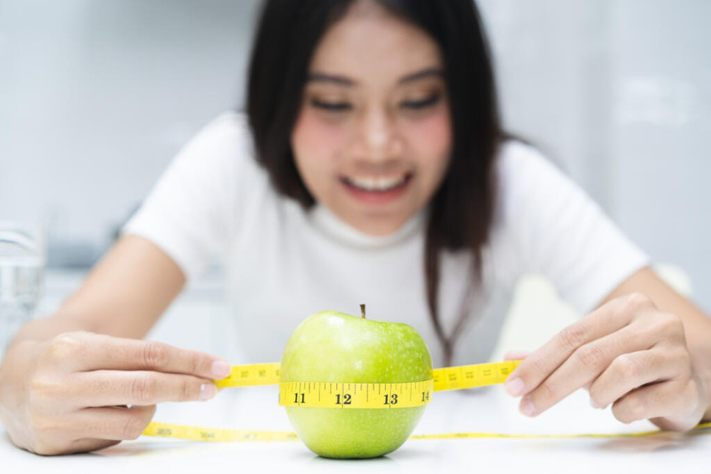 Slimming,And,Dieting,Concept.,Woman,Measuring,Green,Apple.