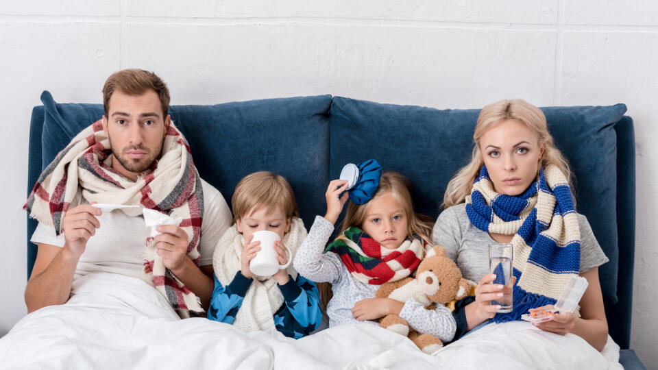 Sick,Young,Family,Sitting,In,Bed,Together,And,Looking,At