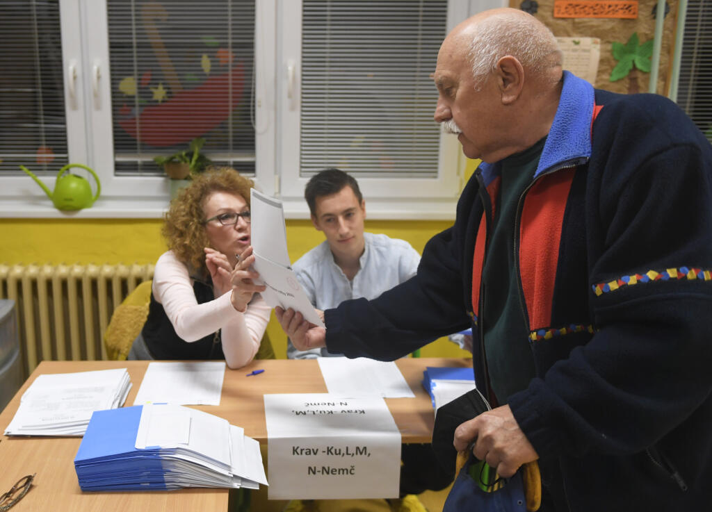 Na Slovensku sa v sobotu o siedmej hodine ráno začali historicky prvé spojené voľby do orgánov samosprávy obcí a do orgánov samosprávnych krajov. Na snímke volič si preberá hlasovacie lístky od členky volebnej komisie vo volebnej miestnosti na ZŠ Hroncova v Košiciach 29. októbra 2022. FOTO TASR – František Iván