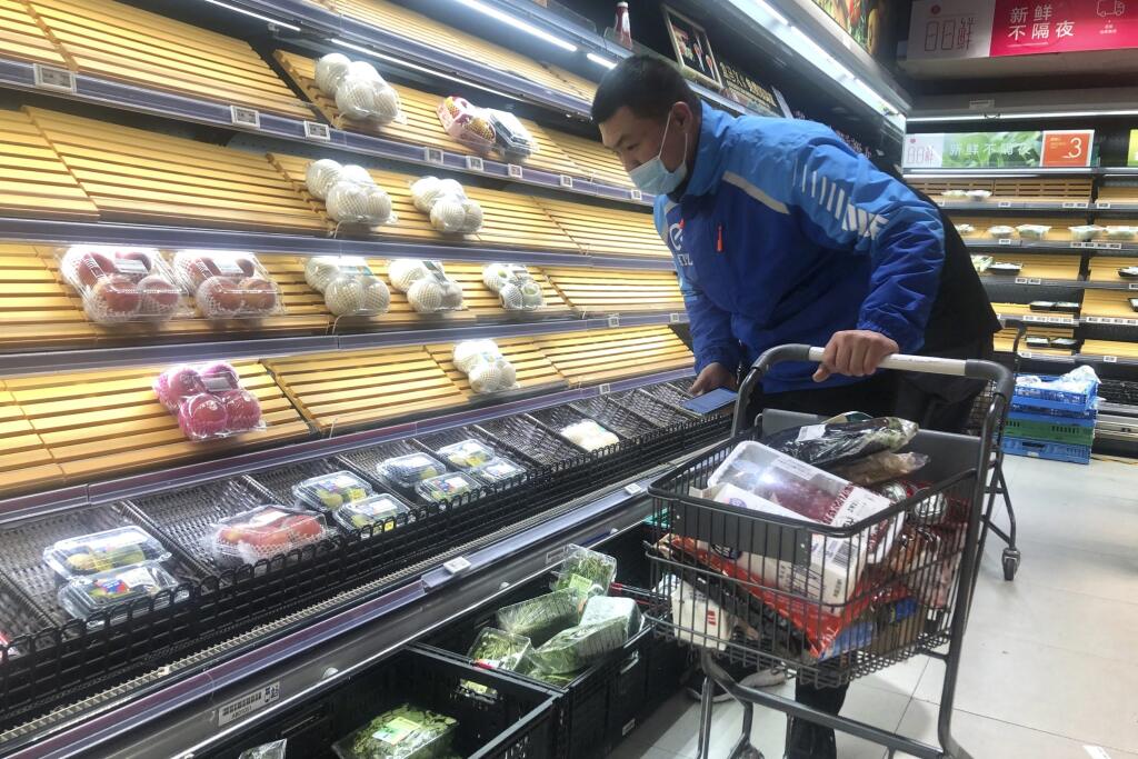 JB 11 Šanghaj - Roznášač jedla vyberá veci z poloprázdnych regálov v supermarkete v čínskom Šanghaji 30. marca 2022. Úrady v Šanghaji začali v stredu uzatvárať niektoré oblasti na západe tohto najľudnatejšieho čínskeho mesta o dva dni skôr, ako pôvodne plánovali. Dôvodom pre lockdown je rýchle šírenie nového koronavírusu, ktorým sa za uplynulý deň nakazilo rekordných takmer 6000 osôb. TASR o tom informuje na základe správy agentúry Reuters. FOTO TASR/AP

A delivery man selects items from partial