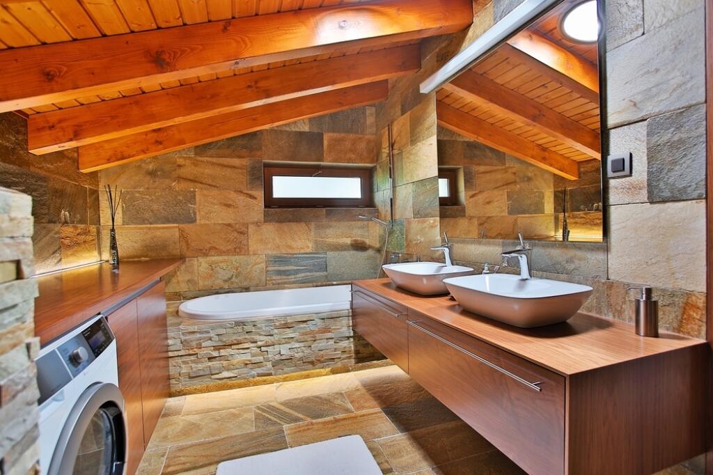 Podkrovná kúpeľňa pôsobí útulne vďaka
obkladu z prírodného kameňa a dreva.
O vzdušnosť sa postaralo veľké zrkadlo
a podsvietenie zabudovanej vane.