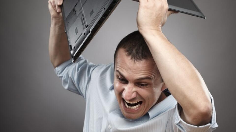 Extremely angry businessman smashing his laptop on the desk