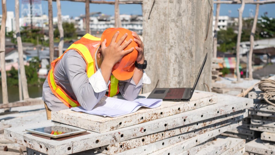 Stress engineer or architect with laptop and tablet holding hands at his head. He is having problems in work. Engineering concept.