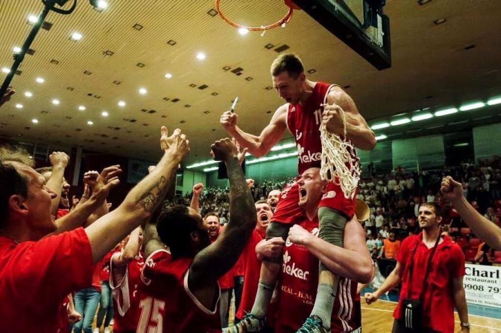 Michal Maslík drží na pleciach spoluhráča, ktorý strihá sieťku na basketbalovom koši.
