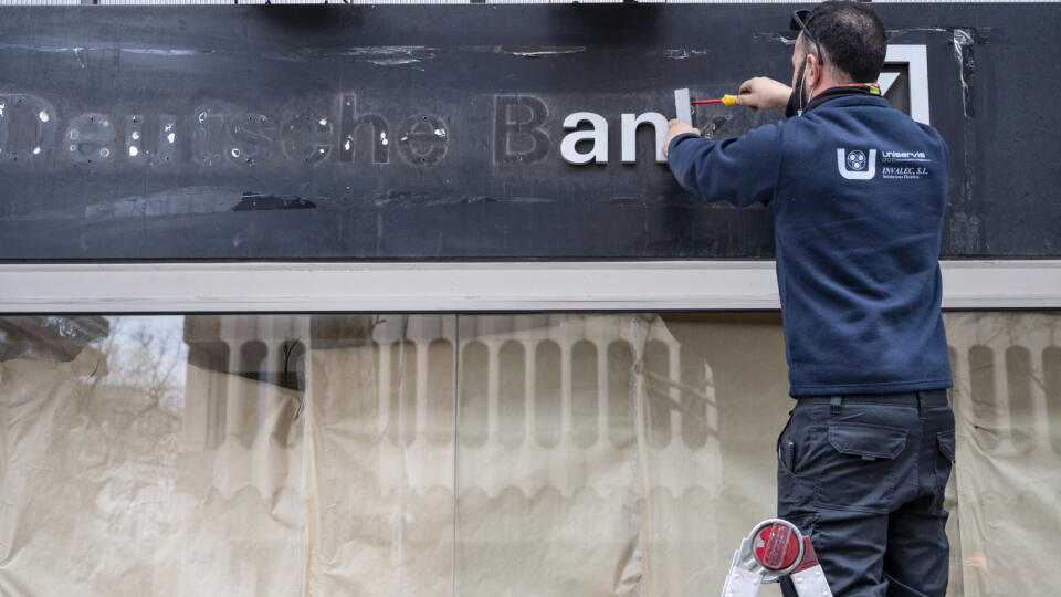 A workers removes the logo of German investment bank and