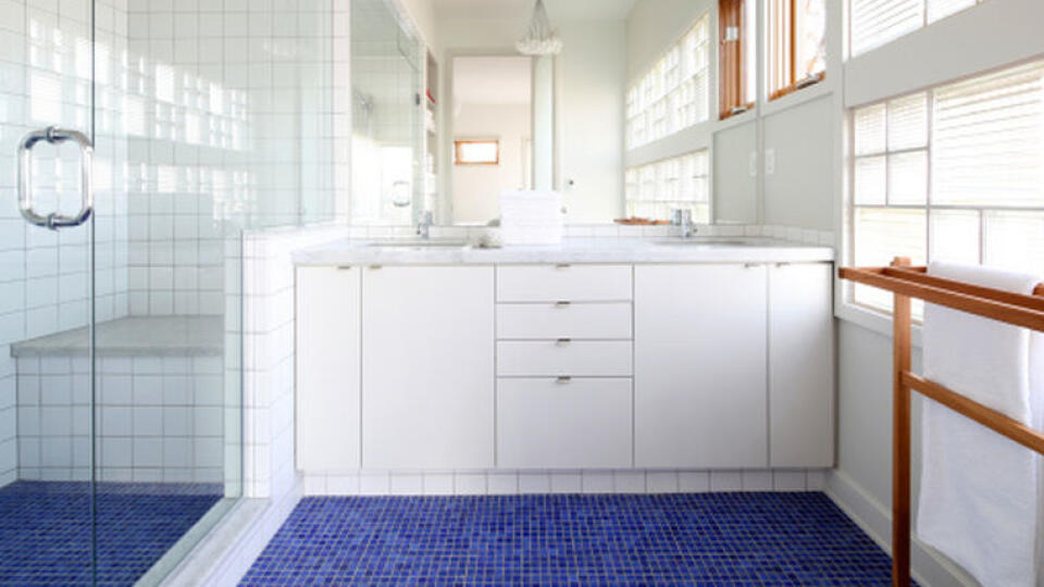 Clean white modern bathroom with blue mosaic tile floor.  