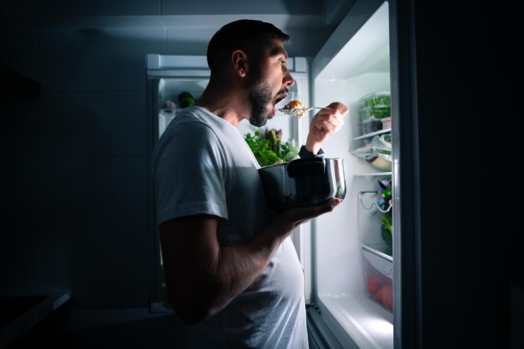 Hungry,Man,Eating,Food,At,Night,From,Open,Fridge.,Man
