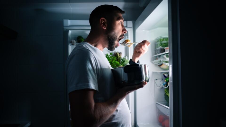Hungry,Man,Eating,Food,At,Night,From,Open,Fridge.,Man