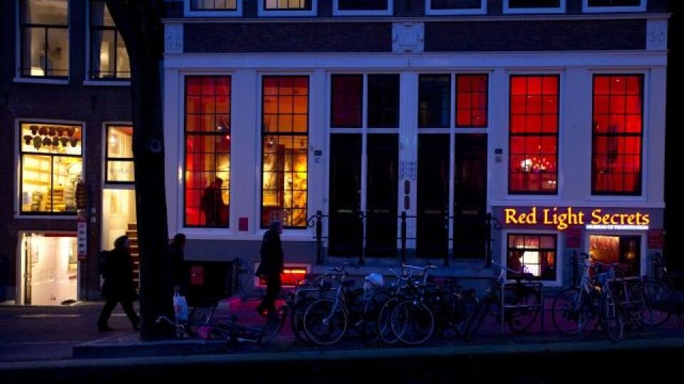In this photo taken Tuesday, Feb. 4, 2014, the entrance of the 'Red Light Secrets' prostitution museum is seen, right, in Amsterdam. On any given evening, thousands of tourists stroll down the narrow streets of Amsterdam's famed Red Light District, gawking at ladies in lingerie who work behind windows, making a living selling sex for money. Now a small educational museum is opening in heart of the district that aims to show reality from the other side of the glass. Organizer Melcher de Wind says