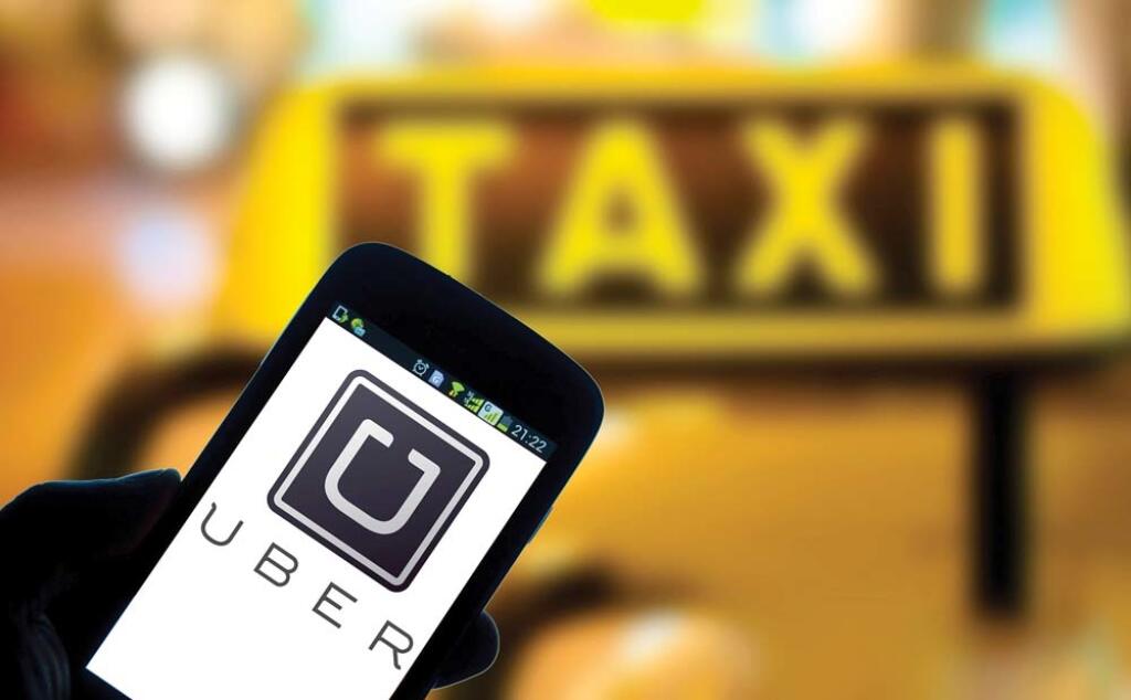 --FILE--A Chinese mobile phone user looks at a logo of taxi-hailing app Uber on his smartphone in Shaoyang city, central China's Hunan province, 10 January 2015. Car hailing service Uber reportedly halted its first round of fundraising where its goal was US$1 billion which was to be used to focus on expansion in China, according to Chinese web portal Tencent. The plan was for the US$1 billion to be raised, along with another US$1 billion injected by Uber into its Chinese unit, to be used to expa