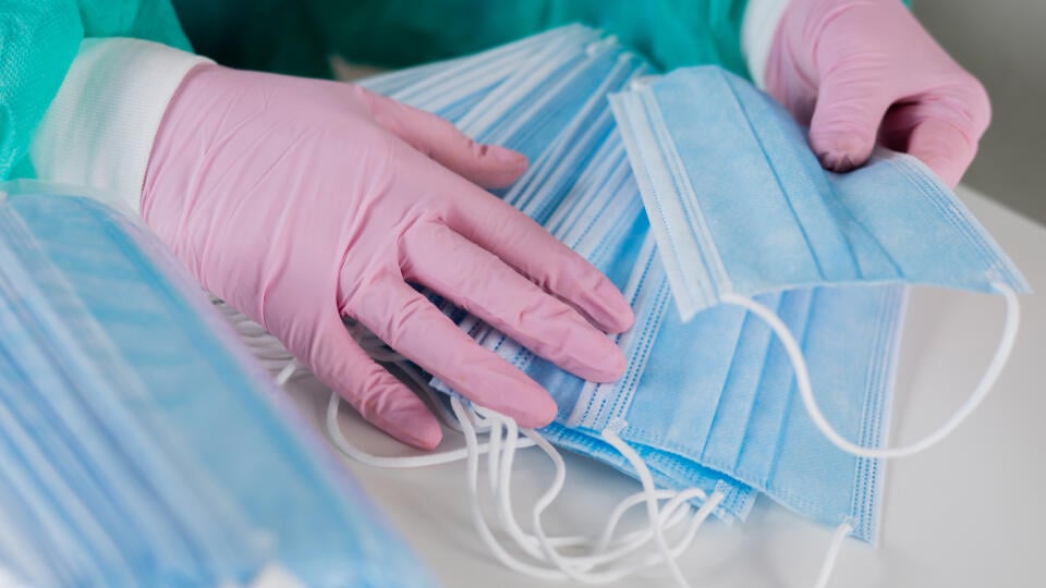 Close-up of women's hands in disposable gloves counting medical masks during the pandemic.