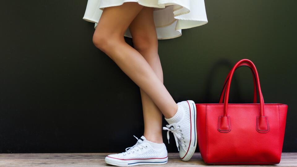 Beautiful fashionable big red handbag standing next to leggy woman