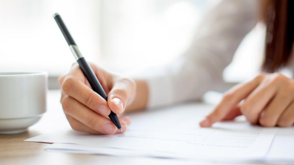 Hand,Of,Businesswoman,Writing,On,Paper,In,Office