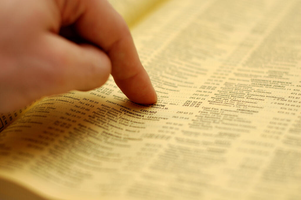 Hand,Pointing,An,Advertisement,In,A,Phone,Book