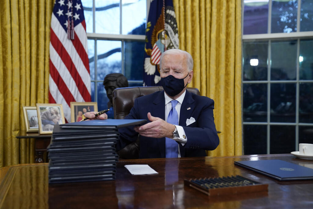 Joe Biden podpisuje prvé dokumenty v Oválnej pracovni Bieleho domu 20. januára 2021 vo Washingtone