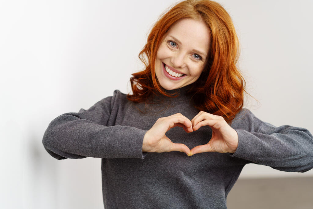Pretty,Romantic,Young,Redhead,Woman,Making,A,Heart,Gesture,With