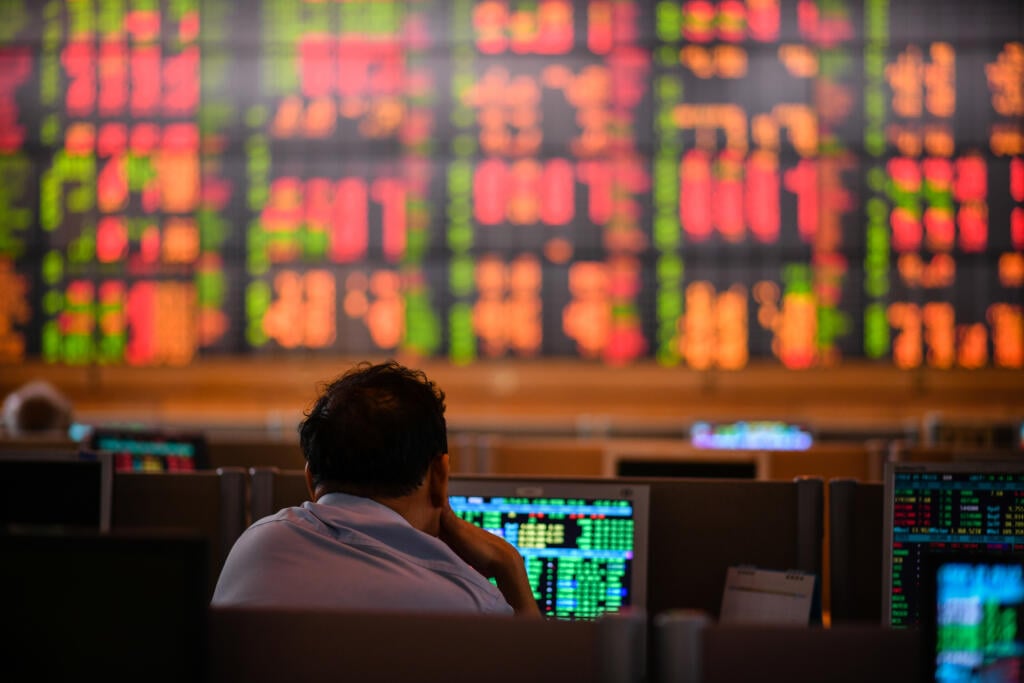 A Thai investor checks an electronic board showing stock