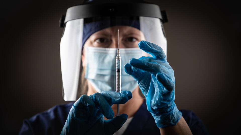 Doctor,Or,Nurse,Holding,Medical,Syringe,With,Needle,Against,Dark