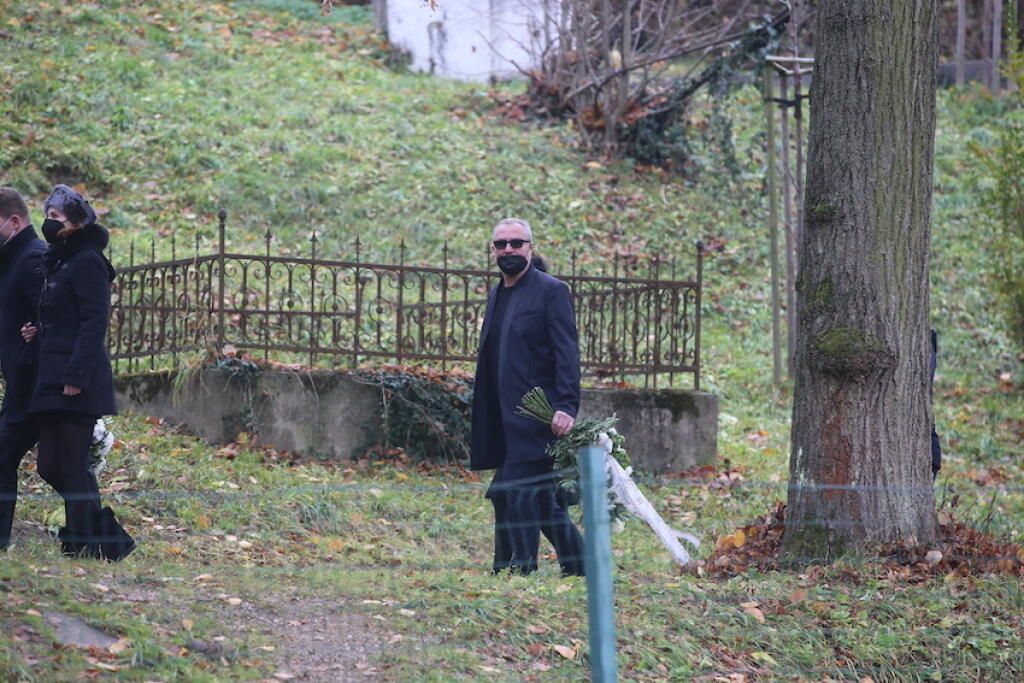 Smútiaci hostia pomaly kráčali za truhlou, ktorú tlačili páni v klobúkoch.