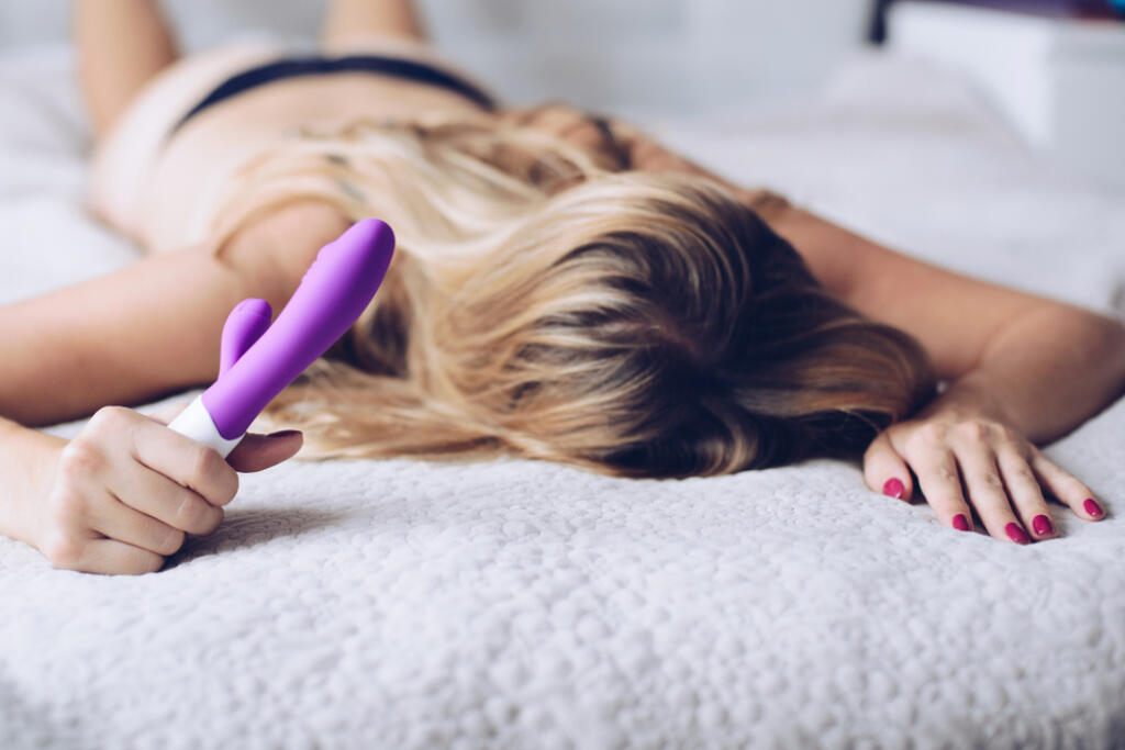 Young,Woman,Holding,Sex,Toy,Dildo,In,Bed