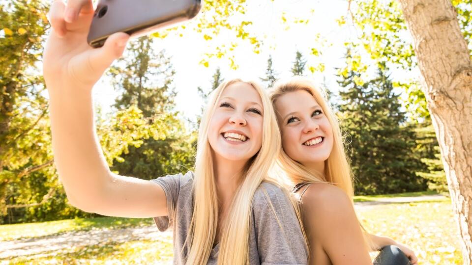 Two sisters having fun outdoors in a city park in autumn and taking selfies of themselves; Edmonton, Alberta, Canada, Image: 292120588, License: Royalty-free, Restrictions: , Model Release: yes, Credit line: Profimedia, Designpics