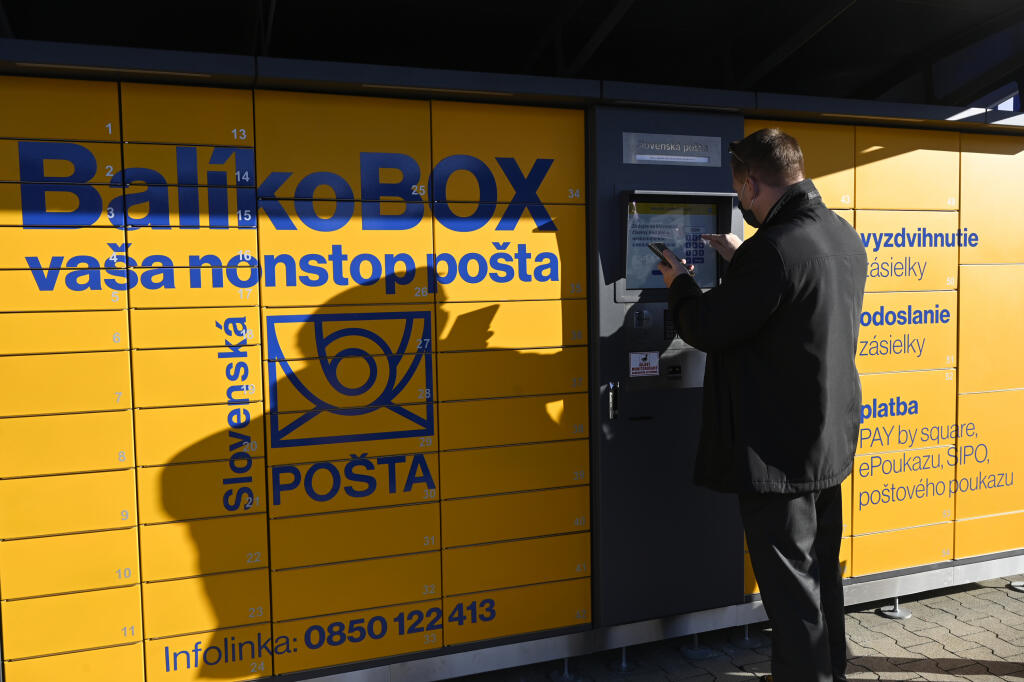 Slovenská pošta spustila prevádzku prvého balíkovoboxu v meste Púchov, 1. februára 2021. Cez balíkoboxy môžu zákazníci okrem vyzdvihovania a podaja balíkov v predplatených obaloch realizovať už aj platobné transakcie, úhradu poštových poukazov, ePoukazy, SIPO či faktúry s PAY by Square kódom. Na snímke predseda predstavenstva Slovenskej pošty Martin Ľupták predvádza, ako si zákazník vyzdvihne balík z balíkoboxu. FOTO TASR - Radovan Stoklasa