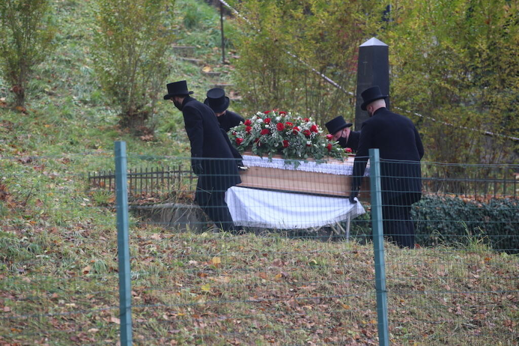 Smútiaci hostia pomaly kráčali za truhlou, ktorú tlačili páni v klobúkoch.