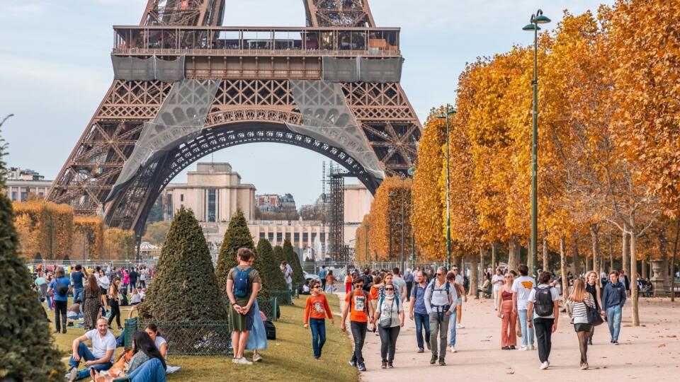 Paris, France - October 2022 : Tourists walking on the Champ de Mars with the Eiffel tower on the background in Autumn in Paris, France