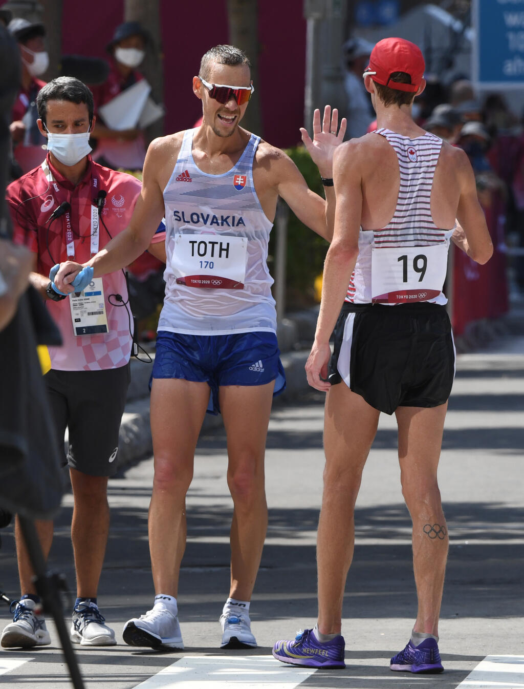 Na snímke slovenský reprezentant v chôdzi na 50 km Matej Tóth (uprostred) sa zdraví s tretím Kanaďanom Evanom Dunfeeom (vpravo) v cieli pretekov na XXXII. letných olympijských hrách 2020 v japonskom Sappore v piatok 6. augusta 2021. Slovenský obhajca zlata z Ria 2016 Matej Tóth obsadil 14. miesto s mankom 6:15 minúty. FOTO TASR - Martin Baumann