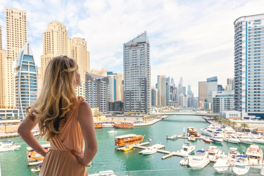 Woman in Dubai Marina, United Arab Emirates. Attractive lady wearing a long dress admiring Marina harbor daylight view