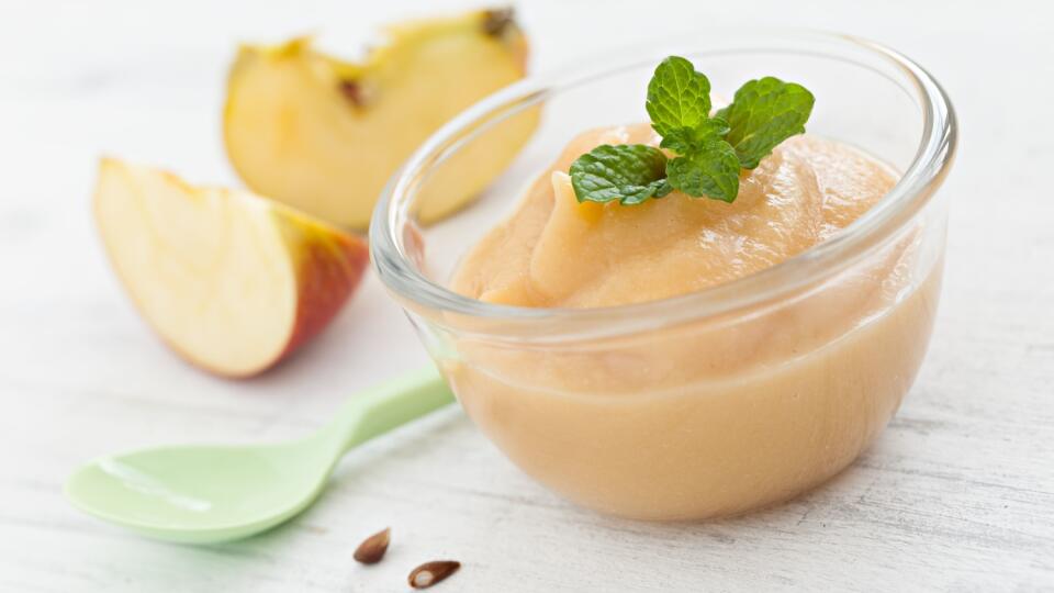 Fresh applesauce in a bowl with apples and a spoon