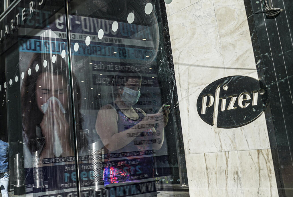 KK27 New York - Na archívnej snímke z 9. novembra 2020 svetové sídlo Pfizeru v NewYorku. Spoločnosti Pfizer a BioNTech požiadajú americký úrad na kontrolu potravín a liekov FDA (Food and Drug Administration) o povolenie na núdzové použitie pre svoju vakcínu proti novému koronavírusu. FOTO TASR/AP FILE - In this Nov. 9, 2020, file photo, an ad for COVID-19 testing reflects on glass at a bus stop, as pedestrians walk past Pfizer world headquarters in New York. On Friday, Nov. 20, 2020, Pfizer has