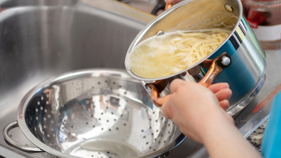 Woman,Separating,Water,From,Spaghetti,With,Empty,Silver,Colander