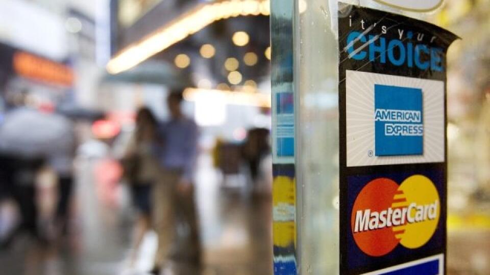 FILE - In this July 27, 2007, file photo, signs for American Express, Master Card and Visa credit cards are shown on a New York store's door. American Express says its net income fell 47 percent in the fourth quarter of 2012, as the credit card issuer racked up hefty charges related to restructuring costs and other one-time expenses. (AP Photo/Mark Lennihan, File)