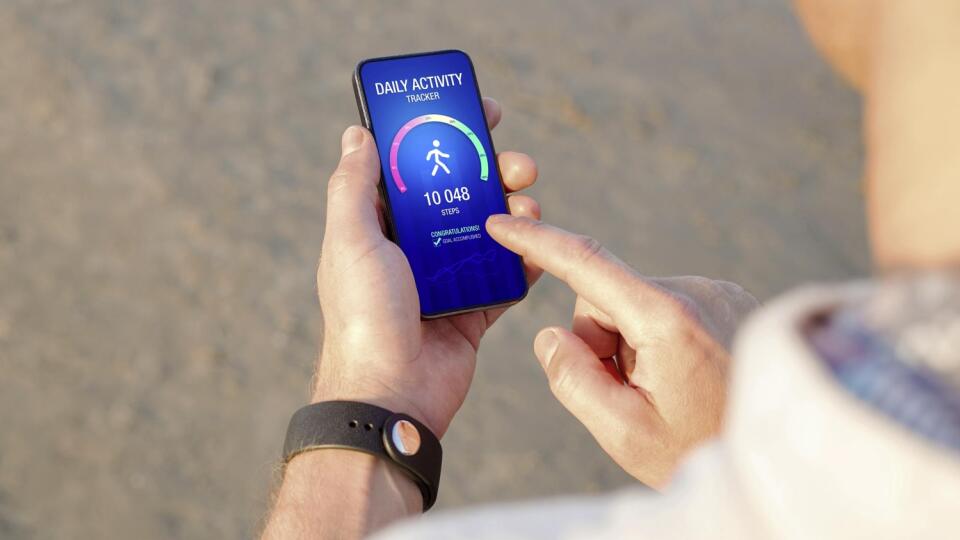 Man using daily activity tracking app on mobile phone showing 10 000 steps daily goal achievement